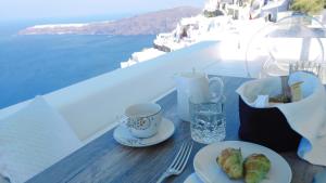 un tavolo con piatti e una tazza di caffè di Andronikos Santorini a Imerovigli
