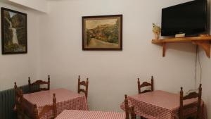 a dining room with two tables and a flat screen tv at Casa Rural López Ordesa in Frajén