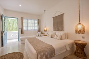 a white bedroom with a large bed and a window at Seaesta Komodo Hotel & Hostel in Labuan Bajo