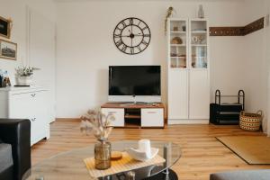 a living room with a tv and a clock on the wall at Ferienwohnung Ohne Gleichen in Sanspareil