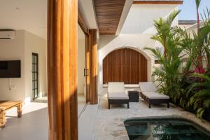 an indoor patio with a pool and a table and chairs at Modern 1BR with Rooftop Rice Fields & Seseh Beach Panorama in Cemagi
