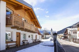a wooden building with a balcony on a snowy street at Dolomiti di Brenta House 2 in Madonna di Campiglio