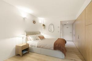 a white bedroom with a bed and a night stand at Pacific Chic Luxury Pad 2 - Beachfront Aircon Lift in Sydney +30 photos