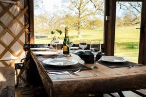 a wooden table with a bottle of wine and glasses at Brenchleyglamping in Tonbridge