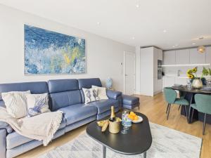 a living room with a blue couch and a table at Skydeck at The Liner – Stylish 2-Bed / 2-Bath Top Floor with Panoramic Sea Views in Falmouth
