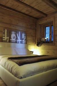 un grande letto in una camera con pareti in legno di Appartamento Le Chalet ad Albosaggia