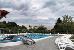a swimming pool with white chairs and a slide at Aquakaros Apartman Zalakaros in Zalakaros