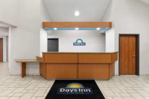 a desk in a room with a day inn sign on the wall at Days Inn by Wyndham Tulsa Central in Tulsa