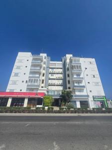 ein großes weißes Gebäude am Straßenrand in der Unterkunft Lazuli Beachfront Sea View Ap 34 in Larnaka