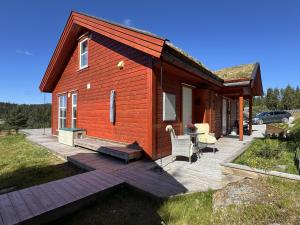 a small cabin with a deck and a table and chairs at Bjørnebo, Family cabin in Torpo