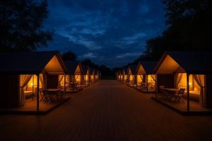 a row of tents with tables and chairs at night at Balmaral Tezami Glamping & Farm Retreat in Tezami