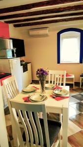 ein weißer Esstisch mit Stühlen und Blumen darauf in der Unterkunft Karmen's Apartment One in Split