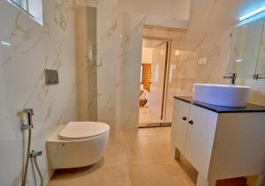 a white bathroom with a toilet and a sink at Central Homestay Ooty by VOYE HOMES Family-Friendly Budget Stay with Valley And Mountain Views in Ooty