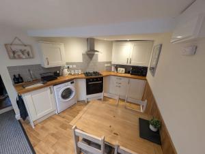 a small kitchen with white cabinets and a wooden floor at Hocking Cottage in Torquay +7 photos