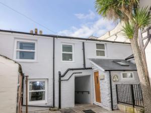 een wit huis met een palmboom ervoor bij Hocking Cottage in Torquay
