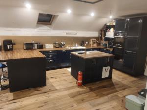 eine große Küche mit schwarzen Geräten und Holzböden in der Unterkunft Upper Barn at the Flax Mill in Coleraine