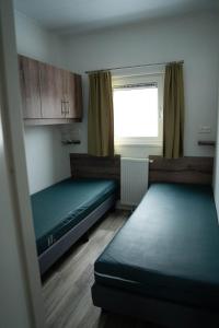 a small room with two beds and a window at Chalet - Camping Natuurlijk Limburg in Remersdaal