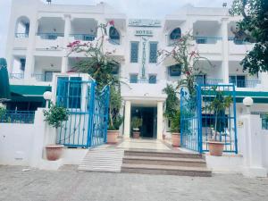 a white building with blue gates and potted plants at Hotel Les Citronniers Hammamet in Hammamet