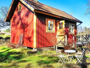 a red house with a table and chairs in front of it at 4 person holiday home in Ellös in Ellos