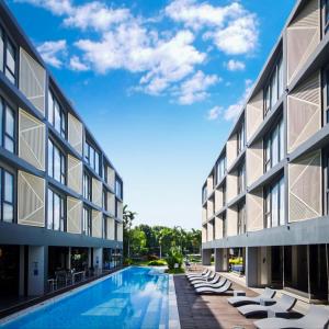 an external view of a building with a swimming pool at Canalis Suvarnabhumi Airport Hotel in Lat Krabang
