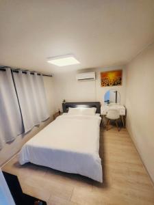 ein Schlafzimmer mit einem großen weißen Bett und einem Schreibtisch in der Unterkunft DDP Families & Friends House in Seoul