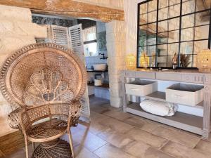 a bathroom with a wicker chair and a sink at LE DOMAINE D'AMBRE La maison des Vendangeurs in Gallician +11 photos