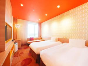 a hotel room with two beds and a television at Hotel Universal Port Vita in Osaka