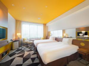 a hotel room with two beds and a television at Hotel Universal Port Vita in Osaka