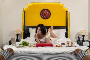 una mujer acostada en una cama con un plato de comida en Grand Fusion Point Hotel, en Hue