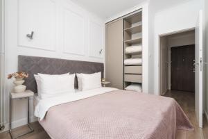 ein weißes Schlafzimmer mit einem großen Bett und einem Kleiderschrank in der Unterkunft Golden Apartments - Luxury Stay for up to 20 Guests in Mennica Residence, Warsaw Center in Warschau