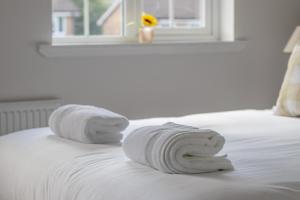 a pile of towels on a bed with a window at Modern 2-Bedroom Home near Glasgow & Edinburgh in Airdrie