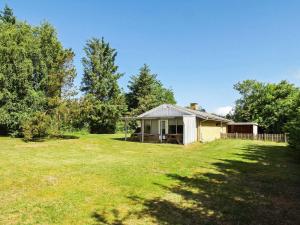 a small house on a grassy field with trees at 2 person holiday home in Tarm in Fjerbæk