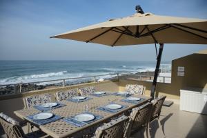 a table with chairs and an umbrella on the beach at Frinton on Sea4 in Ballito