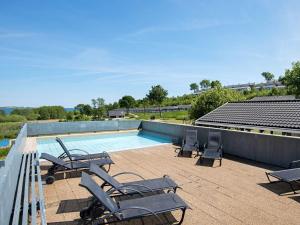 a swimming pool with chaise lounges and chairs on a patio at 6 person holiday home in Aabenraa in Aabenraa