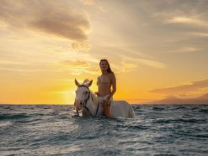 Eine Frau reitet ein Pferd im Ozean in der Unterkunft Cocana Resort Gili Trawangan in Gili Trawangan