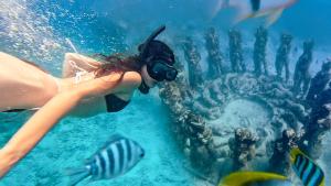 eine Person im Wasser neben einem Riff in der Unterkunft Cocana Resort Gili Trawangan in Gili Trawangan + 88 Fotos