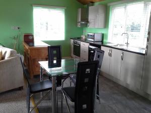 a kitchen with a glass table and a kitchen with green walls at The Cabin,Kings Lane,Weston in Beccles