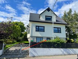 ein weißes Haus hinter einem Zaun mit einem roten Band in der Unterkunft Small cozy rental unit in Strendur Centre in Strendur