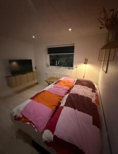 ein Schlafzimmer mit einem Bett mit einer bunten Decke darauf in der Unterkunft Small cozy rental unit in Strendur Centre in Strendur