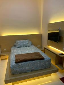 ein Schlafzimmer mit einem Bett und einem Fernseher an der Wand in der Unterkunft House of Toti in Yogyakarta