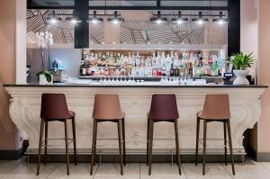 a bar with three stools in front of a counter at NH Bologna De La Gare in Bologna