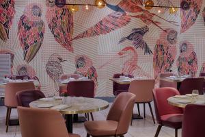 a restaurant with tables and chairs and a mural of birds at NH Bologna De La Gare in Bologna