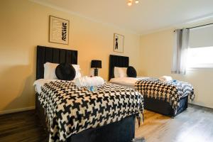 een slaapkamer met 2 bedden met zwart-witte lakens bij 2 BDR Apt At Caledonia Luxe Stays Short Lets & Serviced Accommodation Airdrie in Airdrie