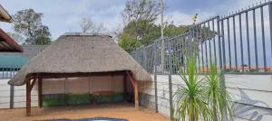 ein Gebäude mit Strohdach neben einem Zaun in der Unterkunft Neema Lodge in Boksburg