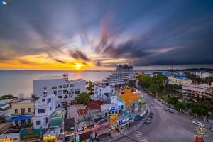 a city with a cruise ship in the ocean at sunset at Monaco Hotel Phú Quốc in Phu Quoc