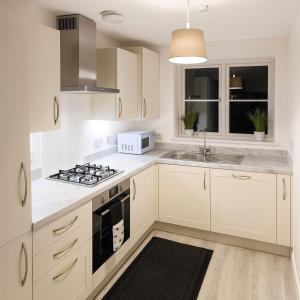 a kitchen with white cabinets and a stove top oven at Halton haven Three bed house sleeps 8 in Halton