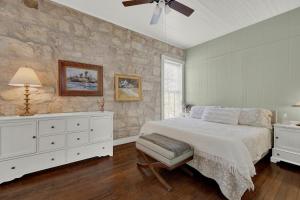 フレデリックスバーグにあるFountain Suite-Stay Right on Historic Main Street in the Heart of Fredericksburgの白いベッドと石の壁が備わるベッドルーム1室