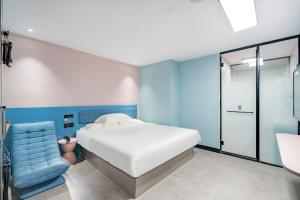 a bedroom with a bed and a blue chair at Hi Inn Beijing Daxing Xingguang Film and Television Park in Beijing