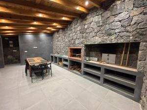 a dining room with a stone wall and a table at Mar D'Abstração in Urzelina