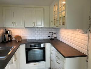 Vreta KlosterにあるSolvik Lakehouse & Outdoor Spaの白いキャビネットとコンロ付きオーブンを備えたキッチン